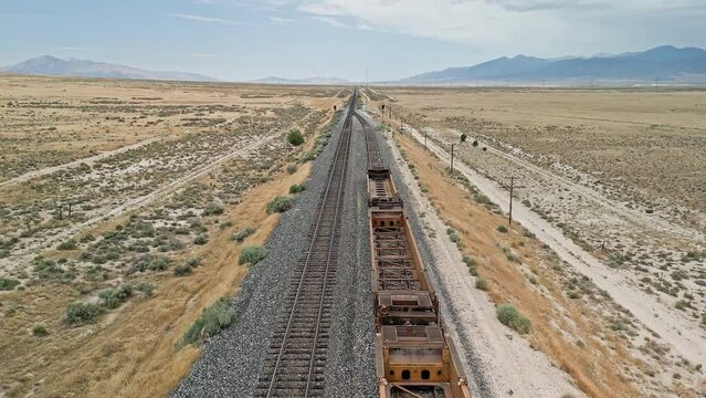 Flying over train tracks where cars are stopped before tracks merge in the Utah desert.