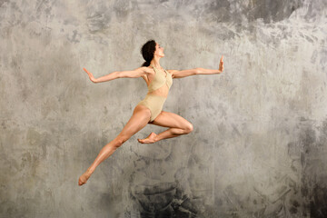 Fototapeta na wymiar Graceful ballerina jumping in studio