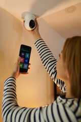 Woman using mobile application to get access to security camera she installed at home
