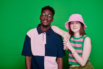 Portrait of stylish multiethnic teenage couple in fashion clothes smiling at camera posing against...