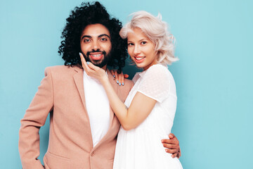 Smiling beautiful woman and her handsome boyfriend. Sexy cheerful multiracial family having tender moments on beige background in studio. Multiethnic models hugging. Embracing each other.Love concept