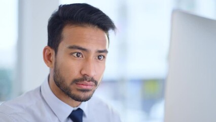 Serious, focused and thinking man reading his emails and browsing online on a desktop computer while working in an office. Professional male corporate worker being careful while doing research