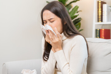 Sick, Coronavirus covid-19 asian young woman, girl headache under blanket have a fever, flu and use tissues paper sneezing nose, runny sitting on sofa bed at home. Health care on virus person.