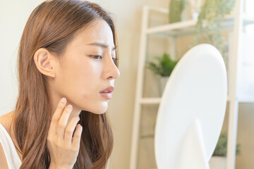 Dermatology, puberty asian young woman, girl looking into mirror, allergy when wear mask and cosmetic, show squeezing pimple spot for removing from face.Beauty care from skin problem by acne treatment - obrazy, fototapety, plakaty