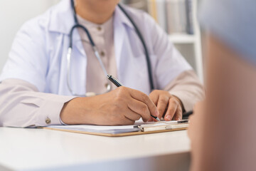 Mature, senior asian physician, psychiatrist woman doctor hand in take note, listen problem consulting concerned with young patient at clinic, hospital. Health care, appointment check up medical.
