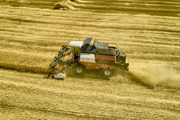 a combine harvester harvesting a field of wheat rural landscape