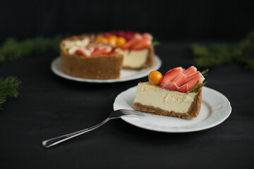 Delicious cheesecake decorated with fruit on a black background