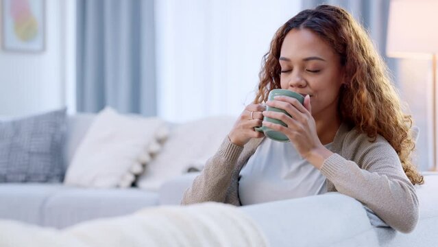 Happy adult woman, morning coffee on sofa. Dreamy female relaxing at home enjoying a fresh cup of coffee on a day off. Lady feeling calm and stress free thinking of the opportunity the day brings.