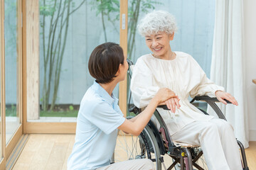 車椅子に乗ったシニア女性と介護士（介護・福祉・ヘルパー）