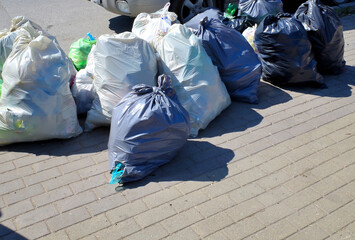 Plastic bags with garbage on the edge of the sidewalk on a summer day