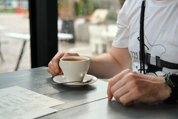 Close-up of male hands with a cup of coffee in modern cafe. Selective focus.