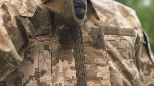 military man in camouflage uniform puts on jacket, close-up