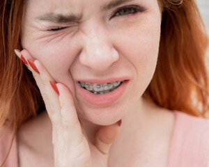 Obraz premium Young red-haired woman with braces suffering from pain. 