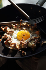 Fried egg with chanterelles and rice in a black frying pan