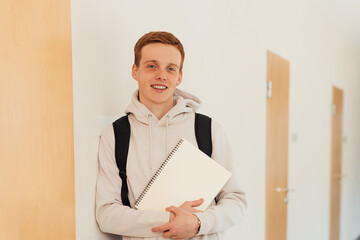 Smiling teenager leaning a wall in high school looking at camera