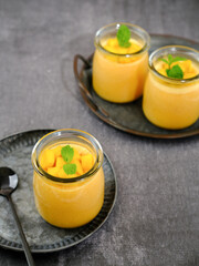 Mango pudding topped with mango chunks and mint leaf garnish. Served in a jar, fresh and healthy
