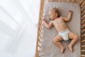 Upper view copy space portrait of cute blond baby sleeping in bed on his back, feeling safe, watching sweet dreams, resting, growing, gaining strength, getting strong. Childcare concept. Nap time - obrazy, fototapety, plakaty