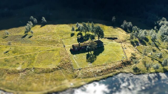 A tilt-shift video of a traditional sod roof house on the river bank. Slow-motion, orbit.