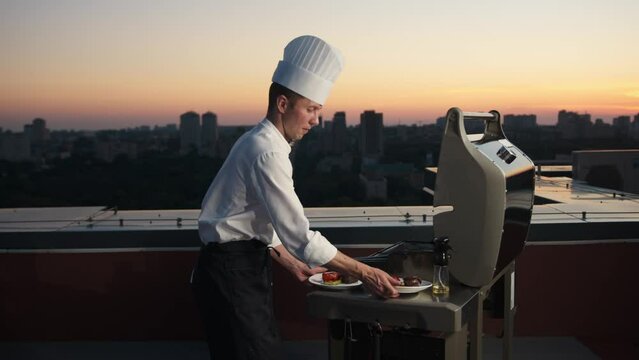 Barbecue: the chef puts filet mignon and vegetables on the plate from the fire on rooftop (grilling)