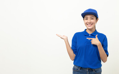 Happy delivery asian woman in blue uniform standing pointing the finger to blank space for text advertise on isolated white background. Smiling female delivery service worker.