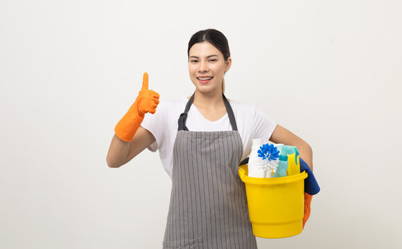 Young housekeeper woman holding bucket of cleaning products ready for cleaning home on isolated white background.