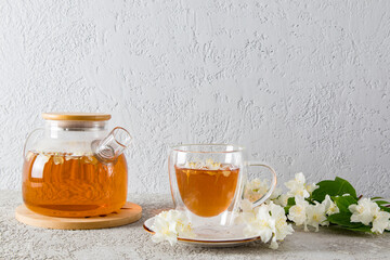 front view of a glass teapot with jasmine tea and a modern cup with a natural delicious drink. gray background. tea time.