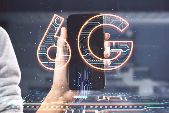 Close up of hand holding smartphone with creative 6G hologram on blurry background. Speed, internet and technology, communication concept. Double exposure.