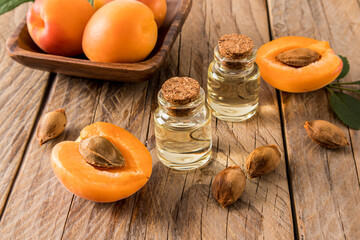 apricot oil in glass bottles on the background of ripe apricots and seeds. wooden background. the concept of rejuvenation, moisturizing the skin.