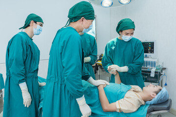 Group of professional medical performing surgery in operating room. Young man and woman surgeons doctor intensive take care accident patient with surgical operation team in emergency room at hospital.