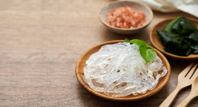 clear kelp or seaweed noodle in a wooden plate and Himalayan salt on wooden background. glass noodle                                                             