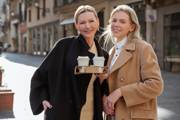 Joyful elegant women posing for the camera in the street