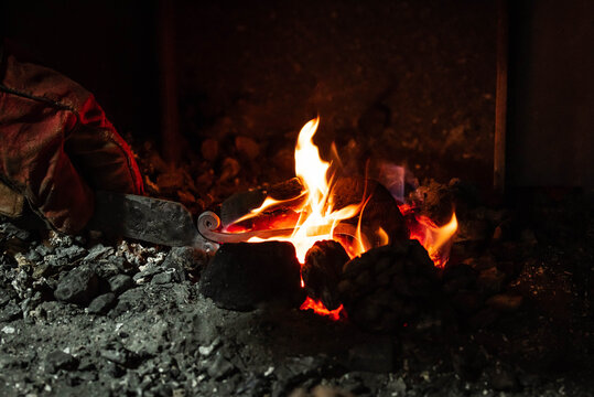 Close up view of heated metal and fire oven. Blacksmith in the production process of other metal products handmade in the forge. Metalworker forging metal into knife. Metal craft industry.