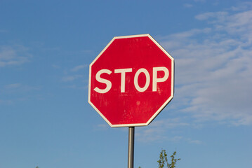 Red Stop Sign with Blue Sky and Clouds Background