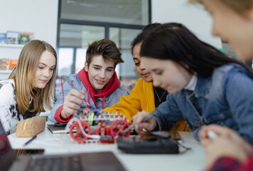 Group of high school students building and programming electric toys and robots at robotics classroom - obrazy, fototapety, plakaty