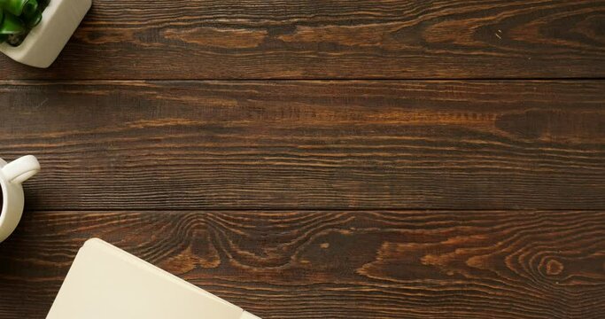 Flatlay with office items and place for text. Layout on a wooden background. Note, pen, a cup of coffee, indoor plant. 4K looped stop motion animation