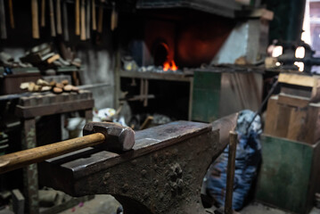 Close up view of heated metal and anvil. Blacksmith in the production process of other metal products handmade in the forge. Metalworker forging metal with a hammer into knife. Metal craft industry.