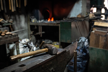 Close up view of heated metal and anvil. Blacksmith in the production process of other metal products handmade in the forge. Metalworker forging metal with a hammer into knife. Metal craft industry.