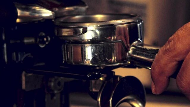 Filling a portafilter with coffee grounds from the grinder on the espresso machine - slow motion