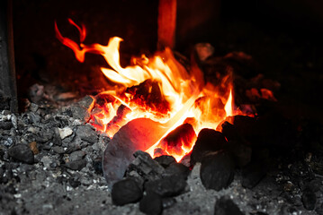 Close up view of heated metal and fire oven. Blacksmith in the production process of other metal products handmade in the forge. Metalworker forging metal into knife. Metal craft industry.