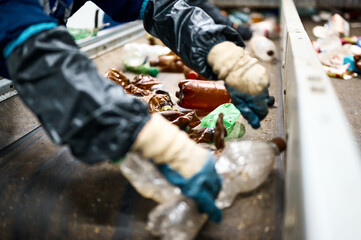 Fototapeta na wymiar Worker sorts trash on conveyor belt at waste recycling plant