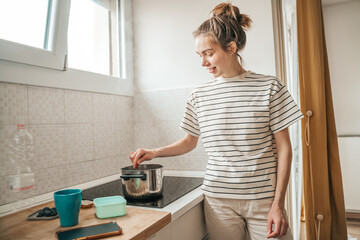 Cheerful housewife cooking breakfast in the morning