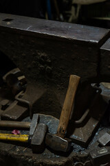 Close up view of heated metal and anvil. Blacksmith in the production process of other metal products handmade in the forge. Metalworker forging metal with a hammer into knife. Metal craft industry.
