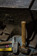 Close up view of heated metal and anvil. Blacksmith in the production process of other metal products handmade in the forge. Metalworker forging metal with a hammer into knife. Metal craft industry.