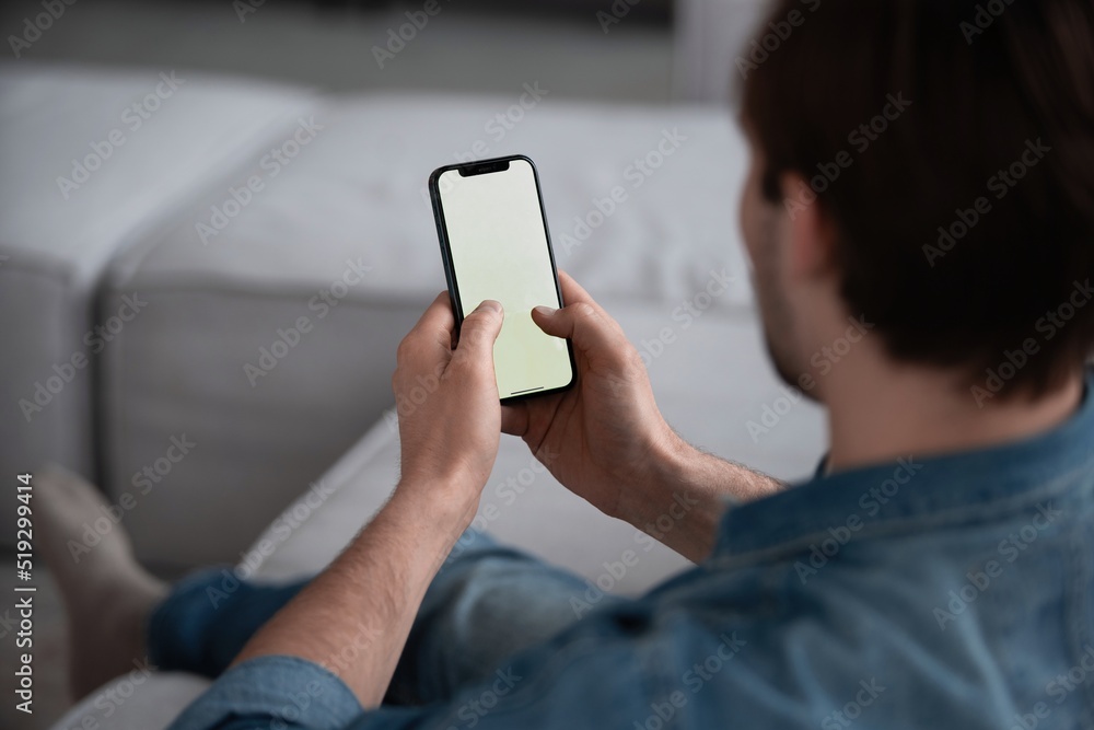 Wall mural unrecognizable man using smart phone with white empty screen for mockup, making video call or chatti