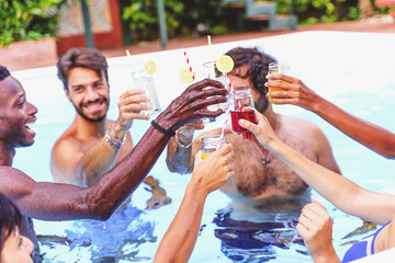 Multiethnic cheerful friends having fun together toasting inside the swimming pool - happy people...