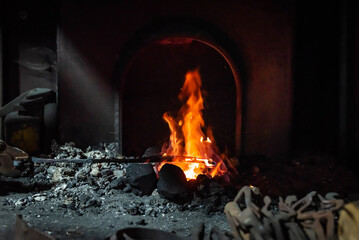 Close up view of heated metal and fire oven. Blacksmith in the production process of other metal products handmade in the forge. Metalworker forging metal into knife. Metal craft industry.