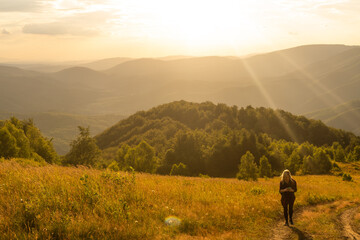 Beautiful woman sitting on mountain top and contemplating landscape.