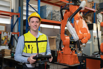 Engineer wearing helmet and hi visible vest working in factory welding robotic automation happy smiling with quality control pass 
