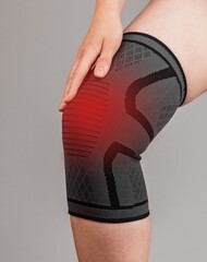 Woman wearing knee brace to reduce pain or prevent injury during sport. Female leg with red point....