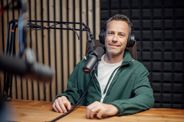 Portrait of mature radio host speaking in microphone while moderating a live show